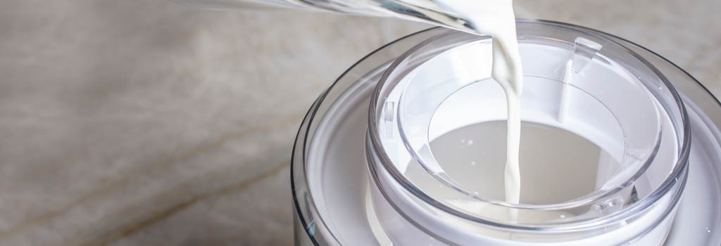 cream being poured into churn ice cream maker